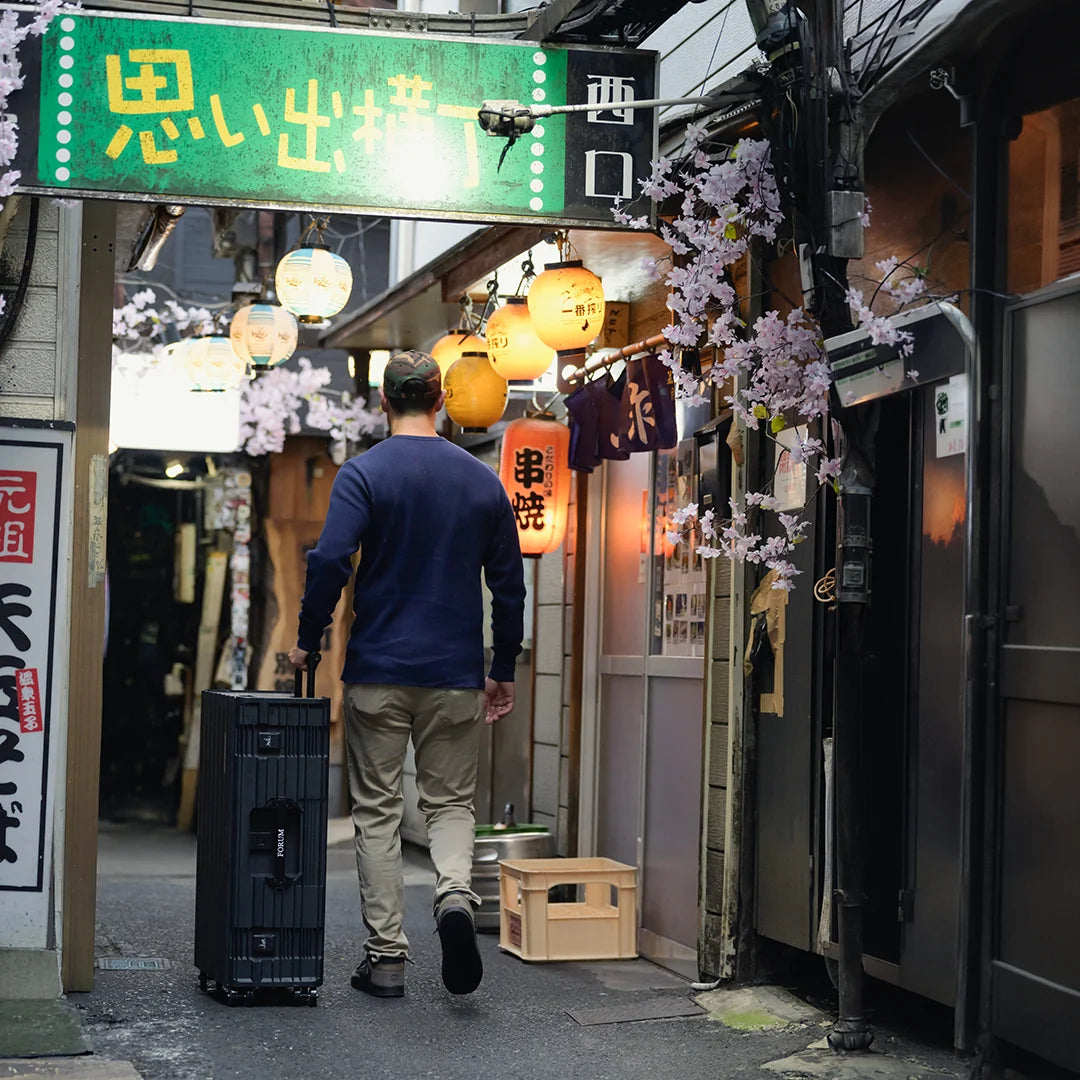 A man pulls the Hades case through a lantern-lit alley in Tokyo
