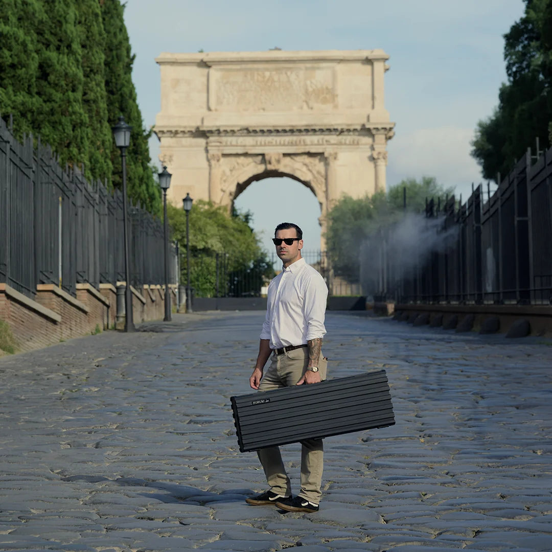 A man carries the Theseus rifle case up the cobbled road to the Arch of Titus in Rome