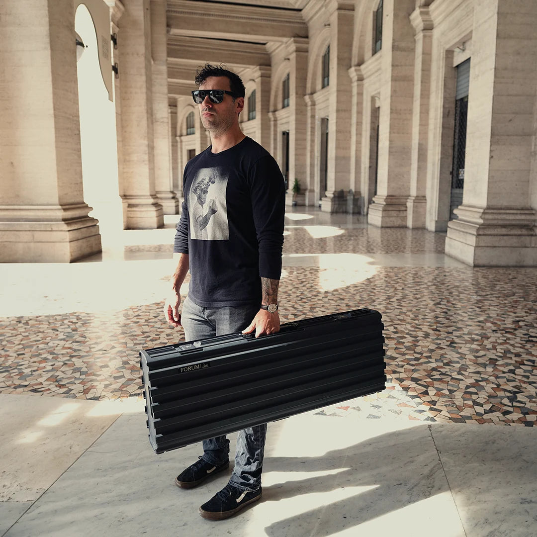 A man holds the Theseus case under a Roman colonnade