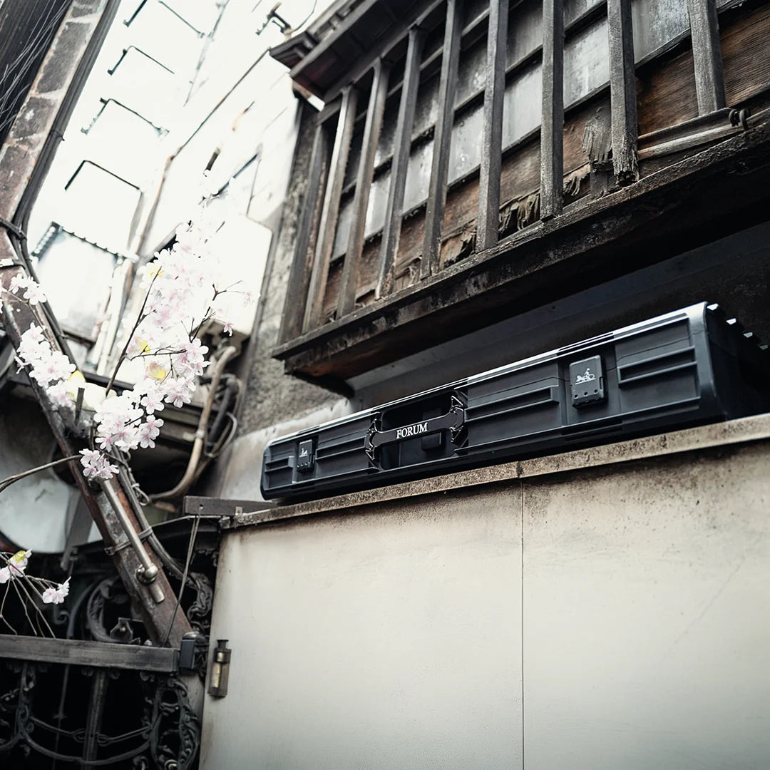 The Theseus case resting on a ledge in a Tokyo alley, cherry blossom beside it